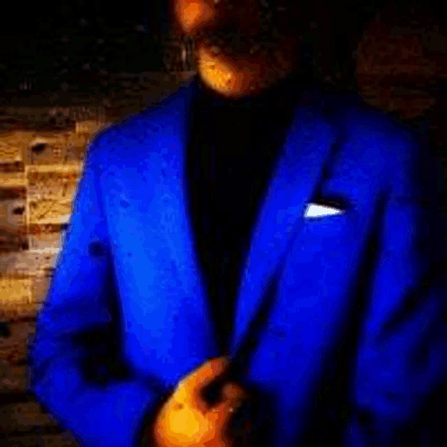 a man in a blue suit is adjusting his collar