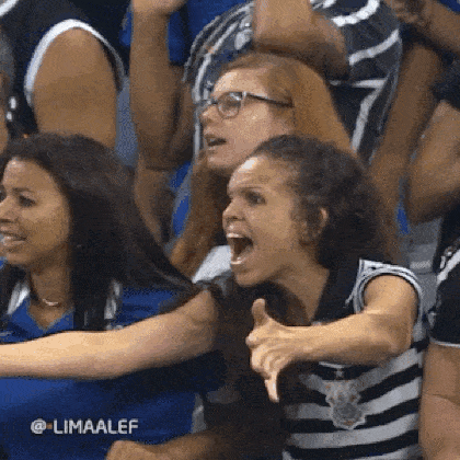 a group of people are sitting in a stadium watching a game and one of them is screaming .