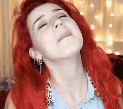 a woman with red hair is making a funny face with her eyes closed and her mouth open .