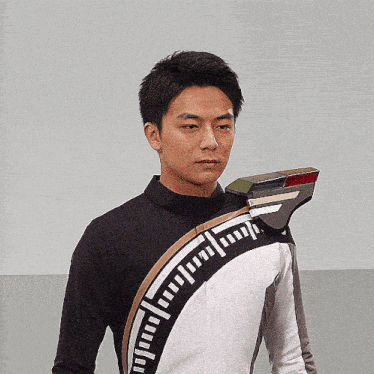 a man wearing a black and white jacket with a measuring device on his shoulder looks at the camera