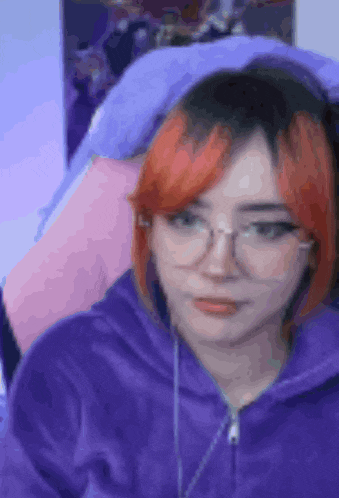 a girl with red hair is wearing glasses and a purple hoodie