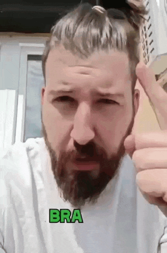 a man with a beard is wearing a white shirt and has the word bra on his chest
