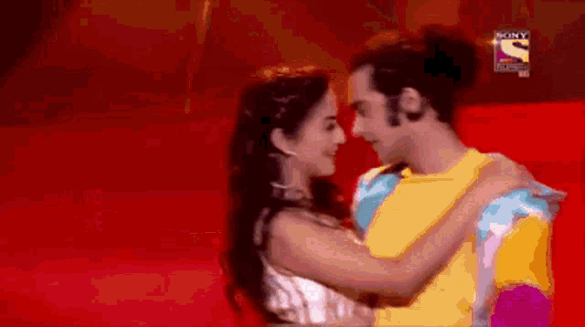 a man and a woman are hugging and looking into each other 's eyes with a sony television logo in the background .