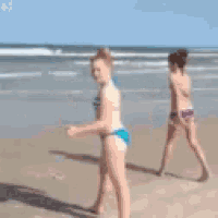 two women in bikinis are running on the beach