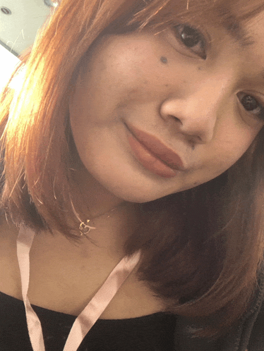 a close up of a woman 's face with a pink lanyard