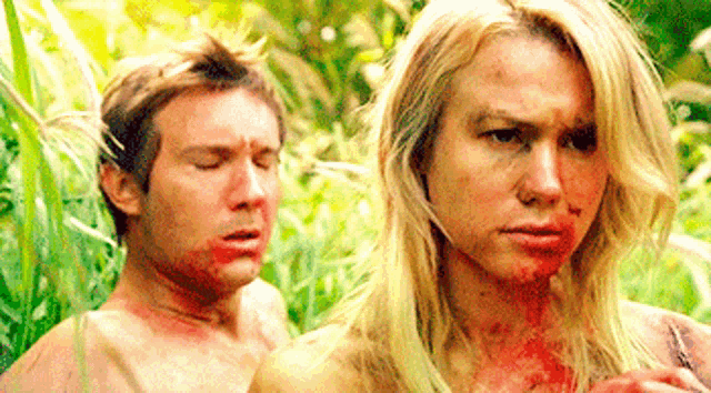 a man and a woman with blood on their faces are standing in the grass