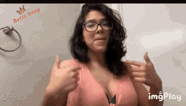 a woman wearing glasses is pointing at her breasts and the words betty boop are above her