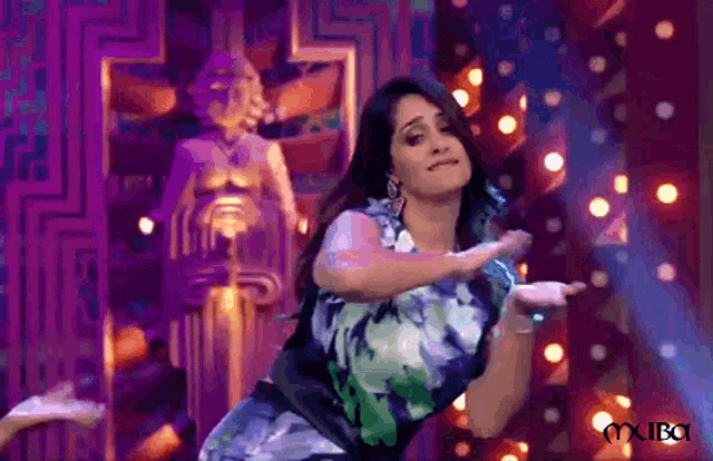 a woman in a floral dress is dancing on a stage in front of a statue .