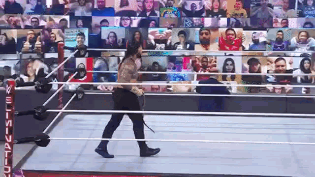 a wrestler is walking out of a wrestling ring with a crowd watching .