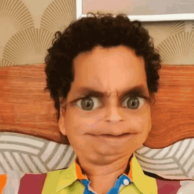 a young boy with curly hair making a funny face while laying on a bed