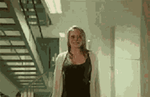 a woman is walking down a hallway next to stairs .