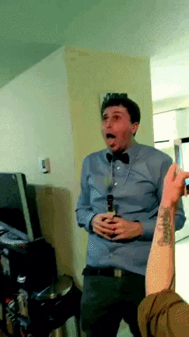 a man in a bow tie holds a bottle of beer in his hand