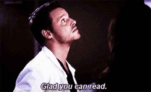 a man in a lab coat is talking to a woman and says glad you can read