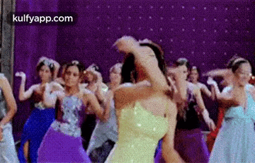 a group of women are dancing on a stage in a room .