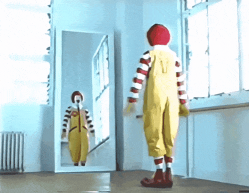 a clown standing in front of a mirror with the letter v on his back