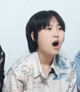 a girl with short hair is wearing a shirt with a map on it and making a surprised face .