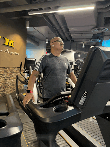a man is running on a treadmill in a gym with a sign that says gym angeles