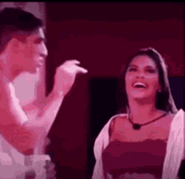 a man and a woman are laughing and talking to each other in a dark room .