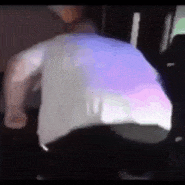 a man in a white shirt is standing in a dark room with a purple background .