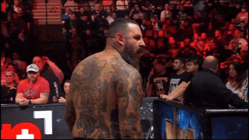 a man with a lot of tattoos stands in front of a crowd