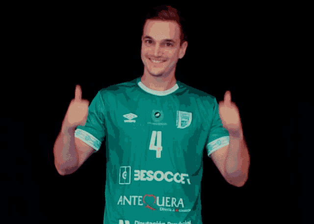 a man wearing a green shirt with the number 4 on it gives two thumbs up