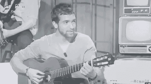 a man is playing a guitar in a black and white photo .