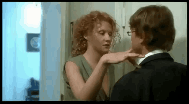 a woman is touching a man 's neck with her hand .