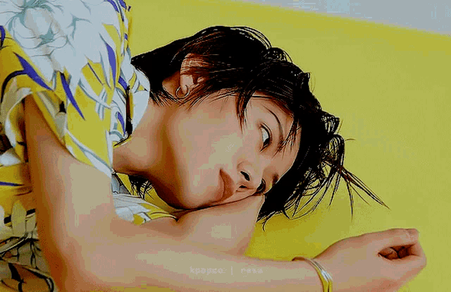 a close up of a person laying on a yellow surface with a bracelet on their wrist ..