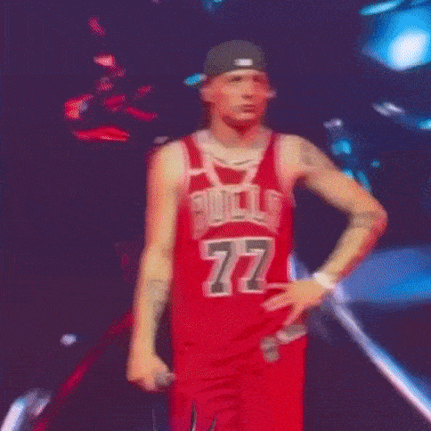a man in a red bulls jersey is standing on a stage with his hands on his hips .