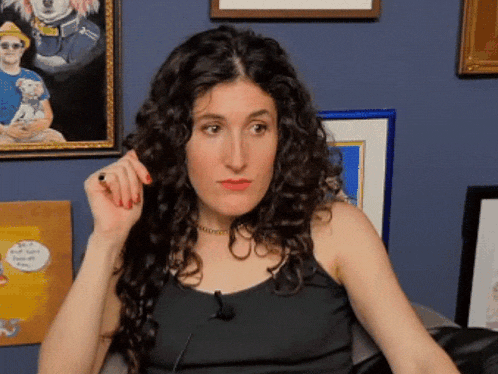 a woman with curly hair is sitting in front of a blue wall