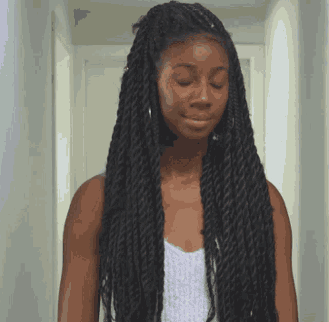 a woman with dreadlocks and hoop earrings looks down with her eyes closed