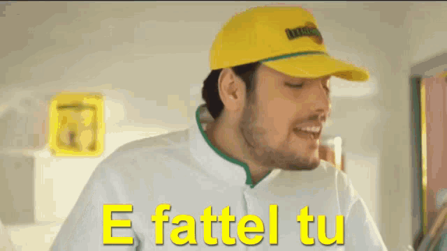 a man wearing a yellow hat and a white shirt says e fattel tu