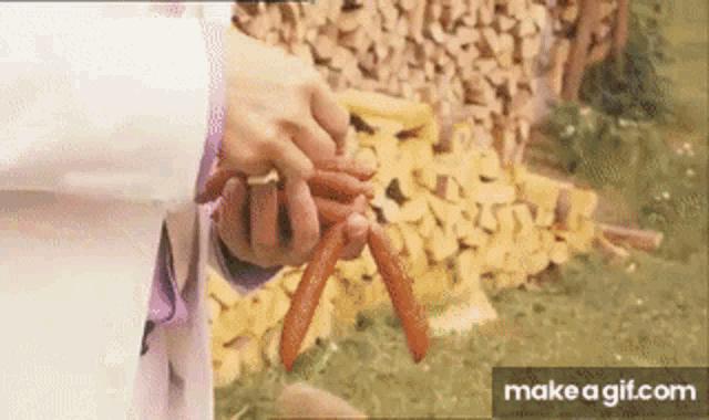 a person is holding a bunch of carrots in their hands in front of a pile of wood ..