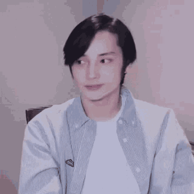 a young man is sitting in a chair wearing a striped shirt and a white shirt .