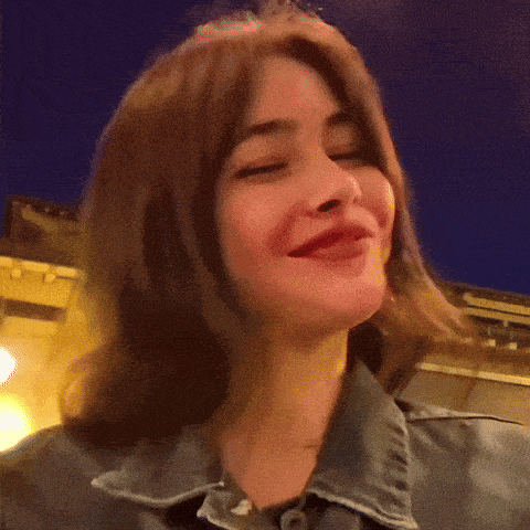 a woman in a denim jacket is smiling and looking at the camera