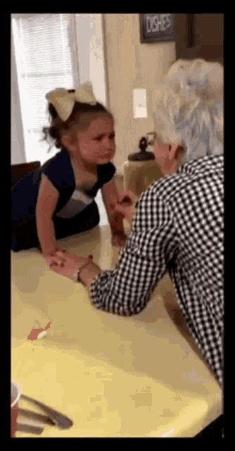 a little girl is crying while sitting at a table with her father .