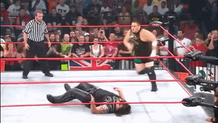 two wrestlers are in a ring with a referee watching