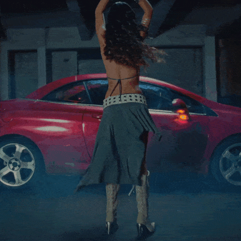 a woman in cowboy boots stands in front of a red car that says ford