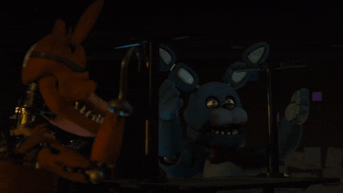 a fox and a blue stuffed animal are standing next to each other in the dark