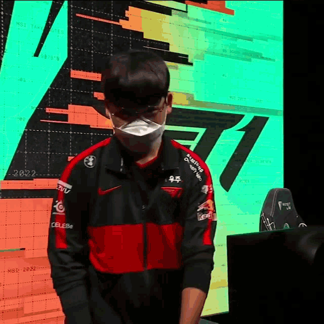 a man wearing a mask stands in front of a screen with the number 1