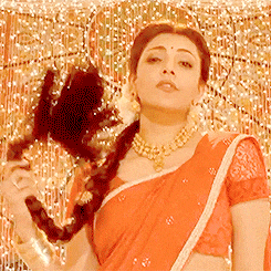 a woman in a red saree is holding a black object in her hand