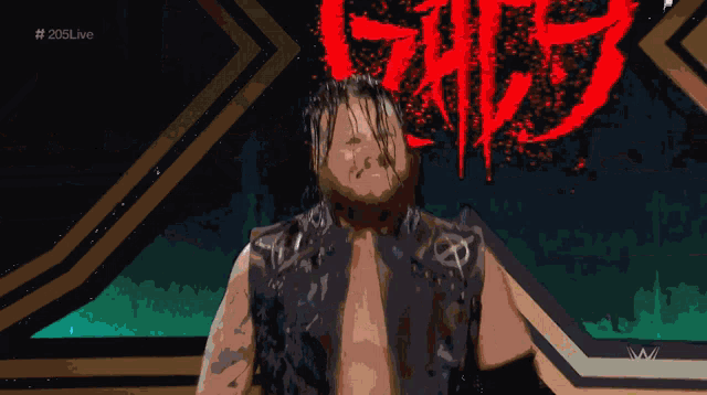 a wrestler is standing in front of a sign that says ' tna ' on it