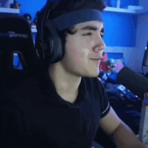 a young man wearing headphones and a headband is sitting in front of a microphone ..