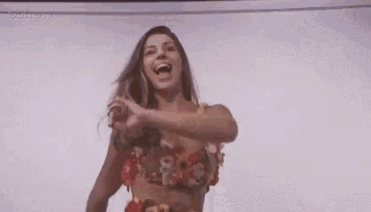 a woman in a hawaiian outfit is dancing with her arms outstretched .