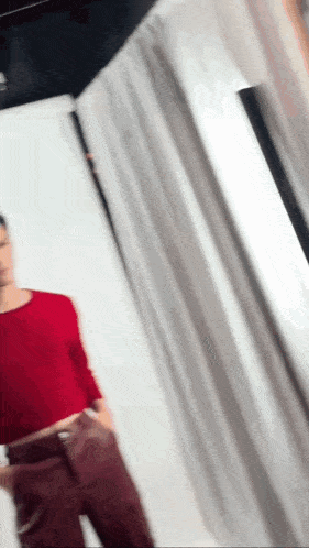 a woman in a red top and red pants is standing in a room