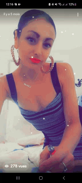 a woman wearing hoop earrings and a necklace has 278 vues written on her phone screen