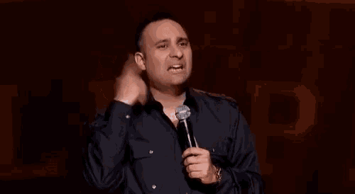 a man is standing in front of a microphone on a stage .