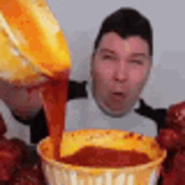 a man is eating a bowl of food while a sauce is being poured into it .