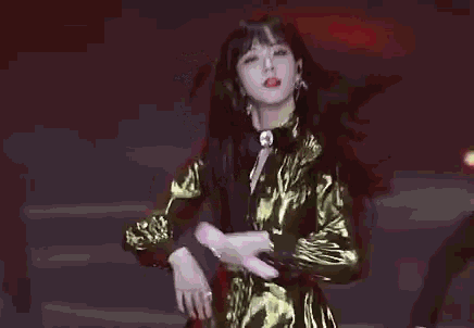 a woman in a gold dress is dancing on a stage .