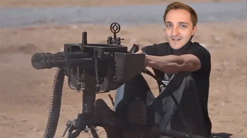 a man in a black shirt is sitting in front of a machine gun with a target on it